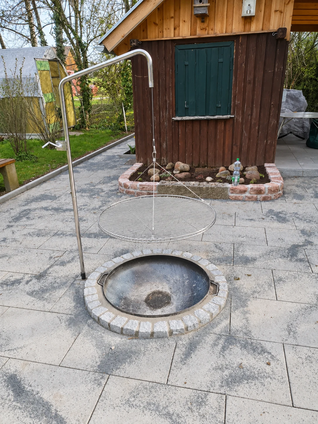Runde Feuerstelle mit Schwenkgrill auf einer Terrasse