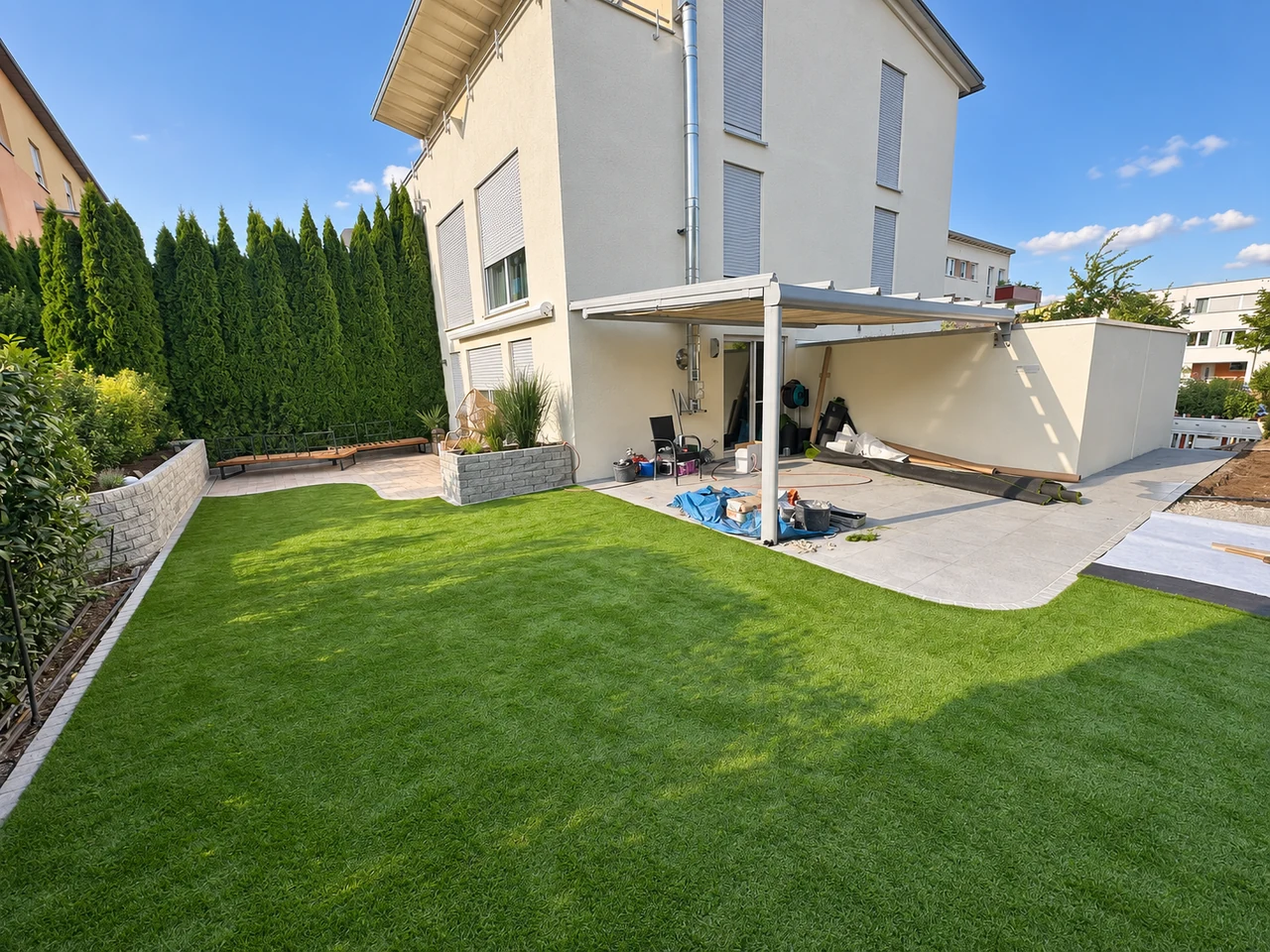 Gartenfläche mit Terrasse und Beeteinfassungen am Haus